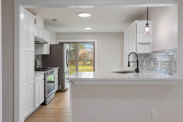 kitchen with white cabinets, kitchen peninsula, hanging light fixtures, and stainless steel gas range oven