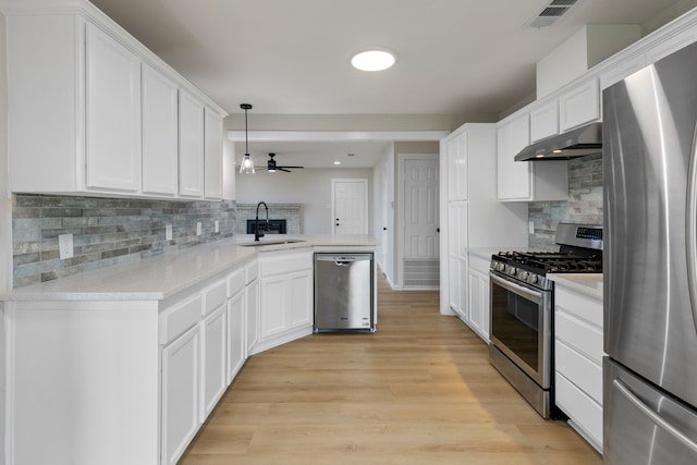 kitchen with sink, white cabinetry, hanging light fixtures, appliances with stainless steel finishes, and kitchen peninsula