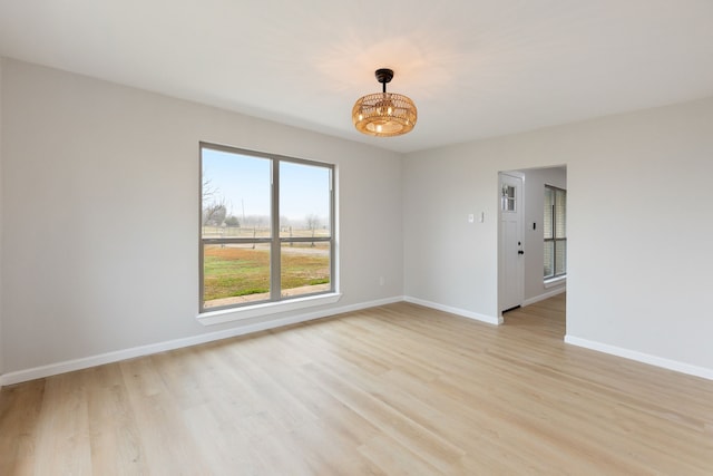 empty room with an inviting chandelier and light hardwood / wood-style floors