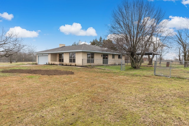 rear view of property featuring a garage and a lawn