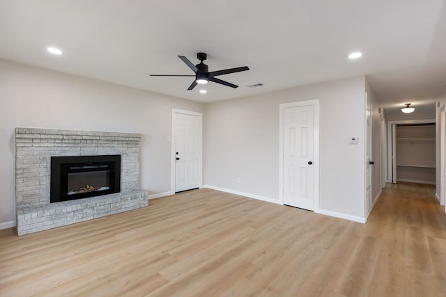 unfurnished living room featuring ceiling fan, a fireplace, and light wood-type flooring