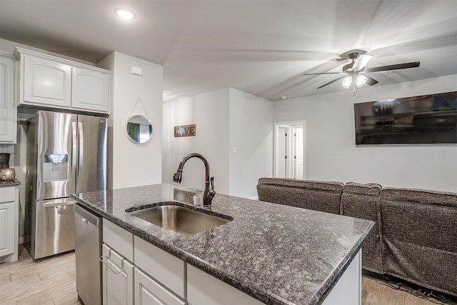 kitchen featuring stainless steel appliances, sink, a center island with sink, and white cabinets