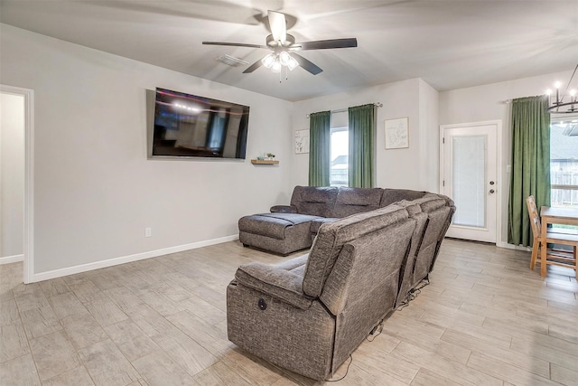 living room with ceiling fan with notable chandelier and light hardwood / wood-style flooring