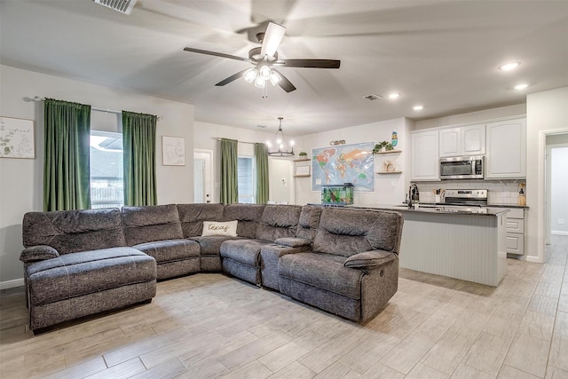 living room featuring sink, ceiling fan with notable chandelier, and light hardwood / wood-style flooring