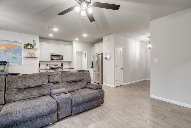 living room featuring sink, light hardwood / wood-style flooring, and ceiling fan