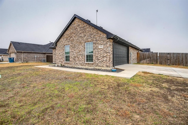 rear view of property featuring a garage, a yard, and central air condition unit