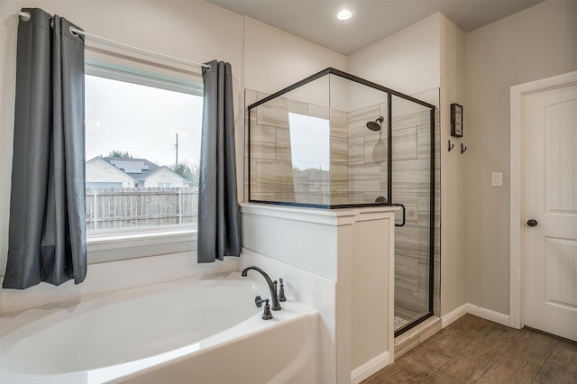 bathroom with shower with separate bathtub and wood-type flooring