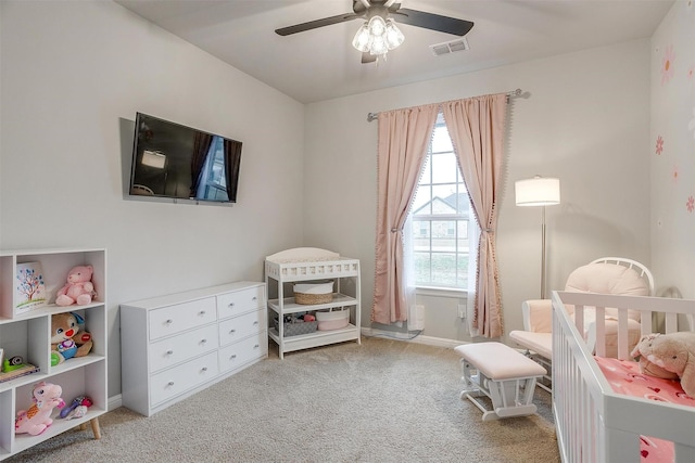 carpeted bedroom with a nursery area and ceiling fan