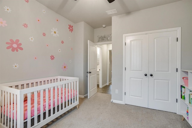 carpeted bedroom featuring a crib, ceiling fan, and a closet