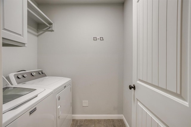 laundry area with cabinets, washing machine and dryer, and hardwood / wood-style floors