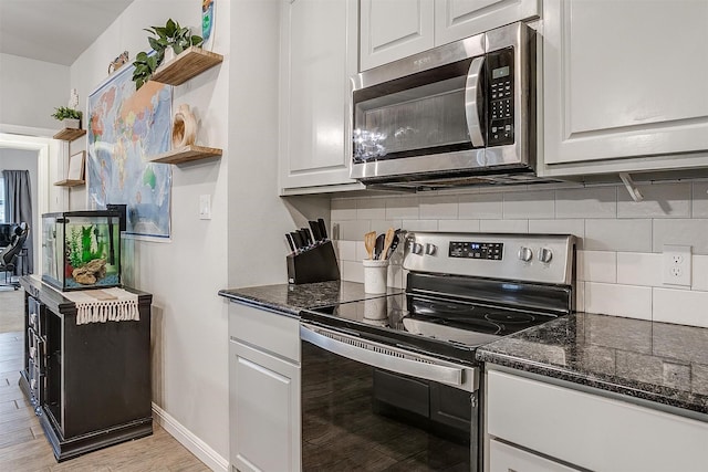 kitchen featuring light hardwood / wood-style flooring, white cabinetry, backsplash, dark stone countertops, and stainless steel appliances