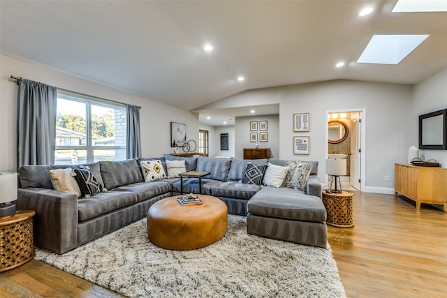 living area with vaulted ceiling with skylight, light wood-style flooring, baseboards, and recessed lighting