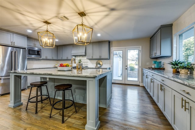 kitchen featuring visible vents, light stone counters, dark wood-type flooring, gray cabinets, and stainless steel appliances