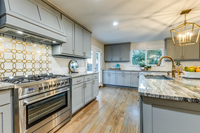 kitchen featuring high end stove, a wealth of natural light, premium range hood, and a sink