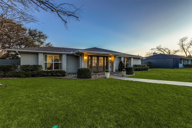 view of front of home featuring brick siding and a lawn