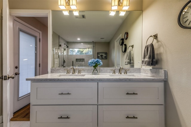 full bath with double vanity, visible vents, a tile shower, and a sink