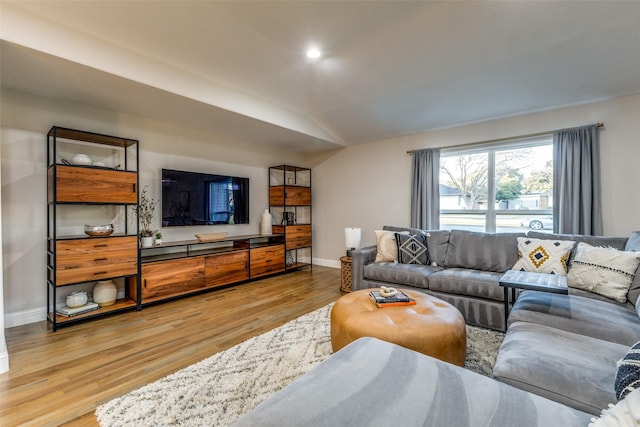 living area featuring vaulted ceiling, baseboards, and wood finished floors