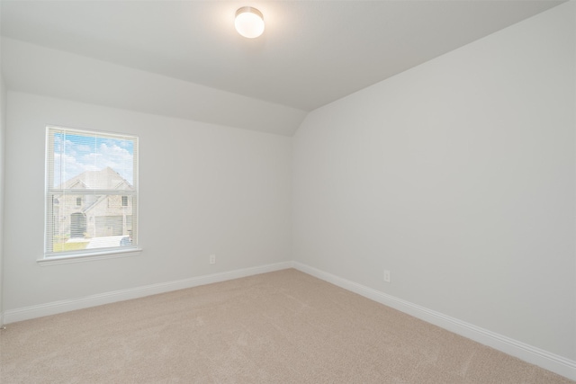 carpeted spare room with lofted ceiling