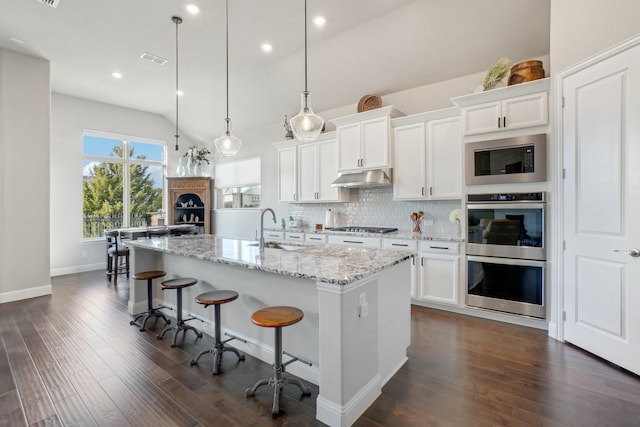 kitchen featuring sink, hanging light fixtures, a center island with sink, appliances with stainless steel finishes, and white cabinets