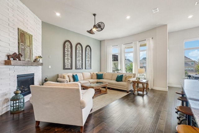 living room with dark hardwood / wood-style flooring, a brick fireplace, and a wealth of natural light