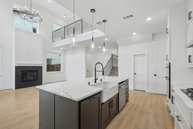 kitchen featuring an island with sink, hanging light fixtures, and white cabinets