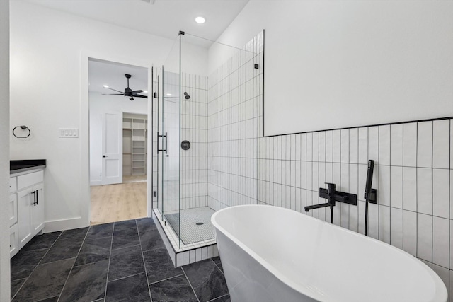 bathroom with vanity, ceiling fan, independent shower and bath, and tile walls