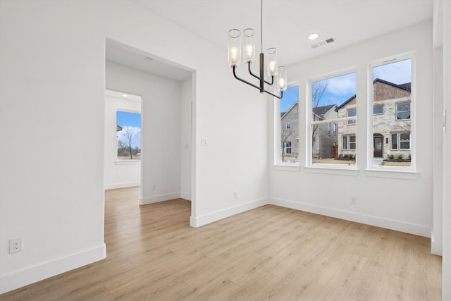 unfurnished dining area featuring light wood-type flooring and a chandelier