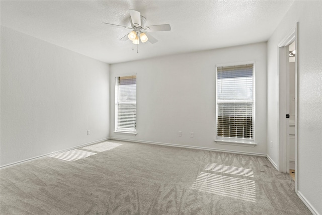 carpeted spare room featuring ceiling fan, plenty of natural light, and a textured ceiling