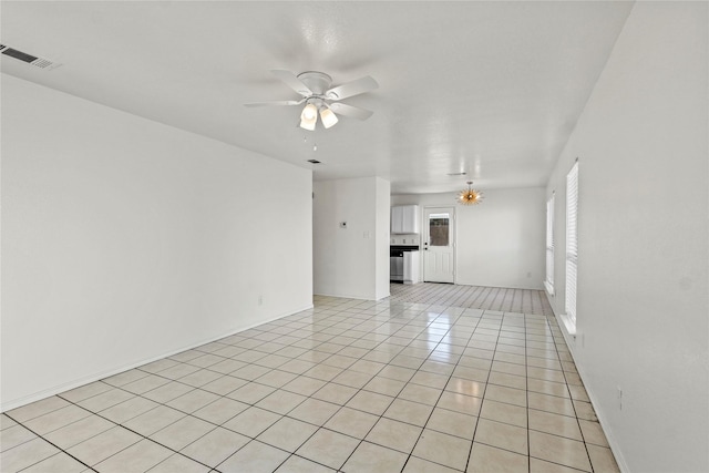 unfurnished living room with ceiling fan with notable chandelier and light tile patterned floors