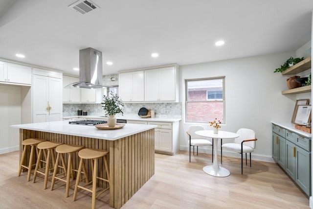 kitchen with light countertops, island exhaust hood, visible vents, and white cabinets