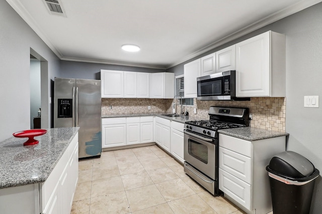 kitchen featuring sink, crown molding, appliances with stainless steel finishes, dark stone counters, and white cabinets