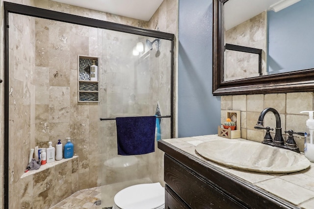 bathroom with vanity, toilet, an enclosed shower, and backsplash