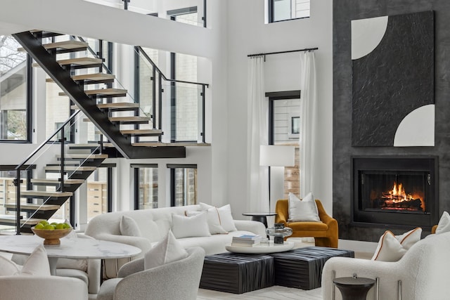 living room featuring a healthy amount of sunlight, a high end fireplace, and a high ceiling