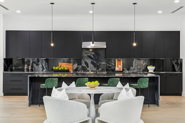 kitchen with decorative light fixtures, light hardwood / wood-style floors, decorative backsplash, and a spacious island