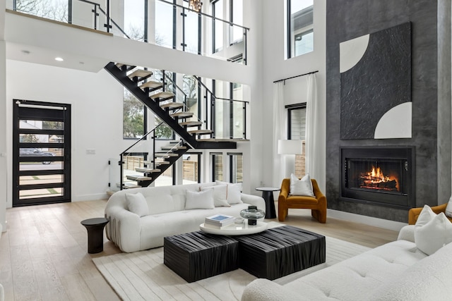 living room with a large fireplace, wood-type flooring, and a towering ceiling