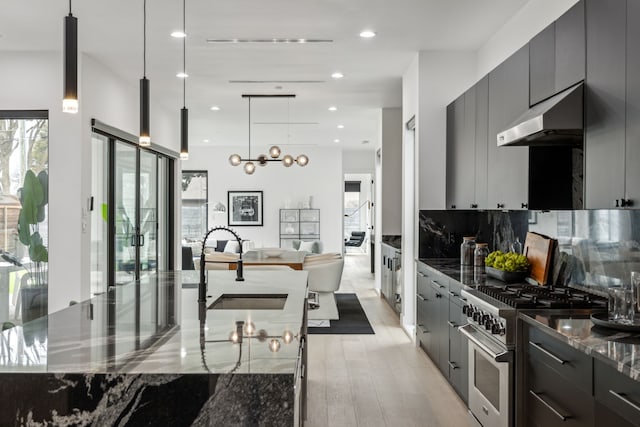 kitchen featuring pendant lighting, a large island, sink, backsplash, and stainless steel range