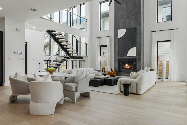 living room featuring a large fireplace, light hardwood / wood-style floors, and a towering ceiling