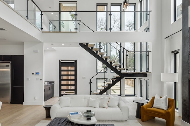 living room featuring a towering ceiling and light hardwood / wood-style floors