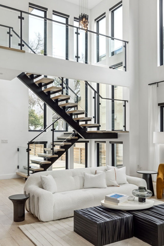 living room featuring wood-type flooring, a towering ceiling, and an inviting chandelier