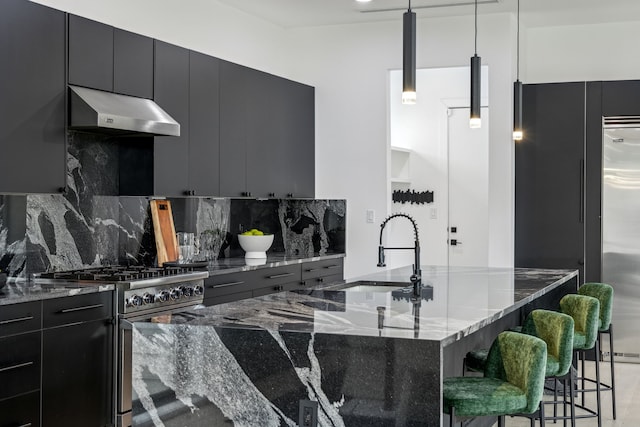 kitchen featuring a kitchen bar, extractor fan, hanging light fixtures, premium appliances, and dark stone counters