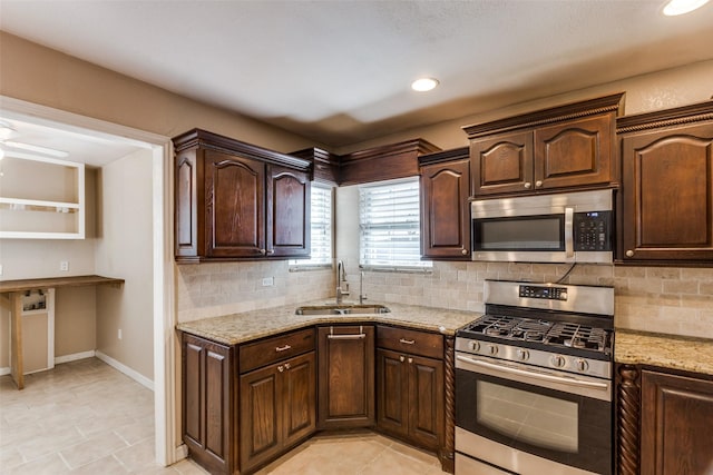 kitchen featuring stainless steel appliances, light stone countertops, sink, and decorative backsplash