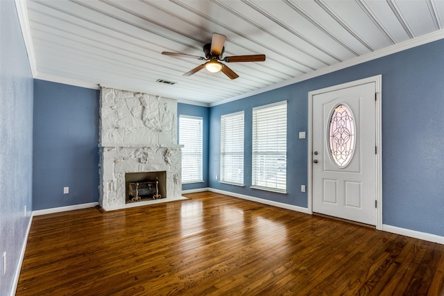 foyer entrance with ceiling fan, crown molding, a fireplace, and wood-type flooring