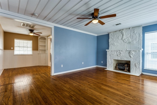 unfurnished living room featuring ornamental molding, a stone fireplace, dark wood-type flooring, and ceiling fan