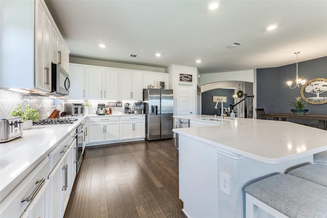 kitchen featuring appliances with stainless steel finishes, sink, white cabinets, a chandelier, and hanging light fixtures