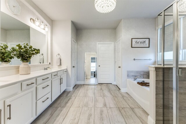 bathroom featuring vanity, a notable chandelier, and a bathing tub