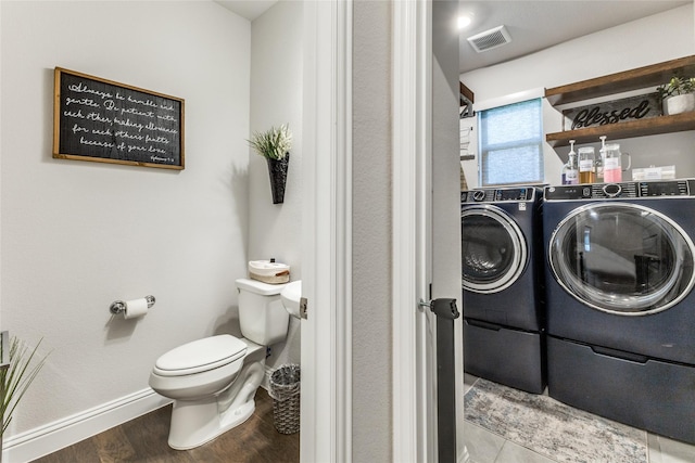 bathroom with wood-type flooring, washer and clothes dryer, and toilet