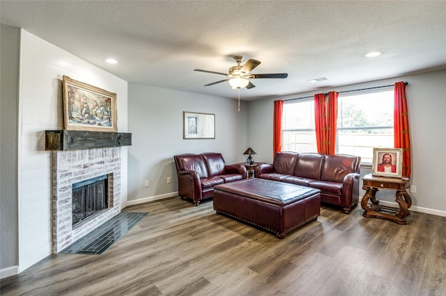 living room featuring hardwood / wood-style flooring, ceiling fan, a textured ceiling, and a fireplace