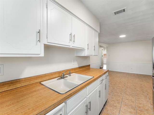 kitchen with light tile patterned floors, sink, and white cabinets