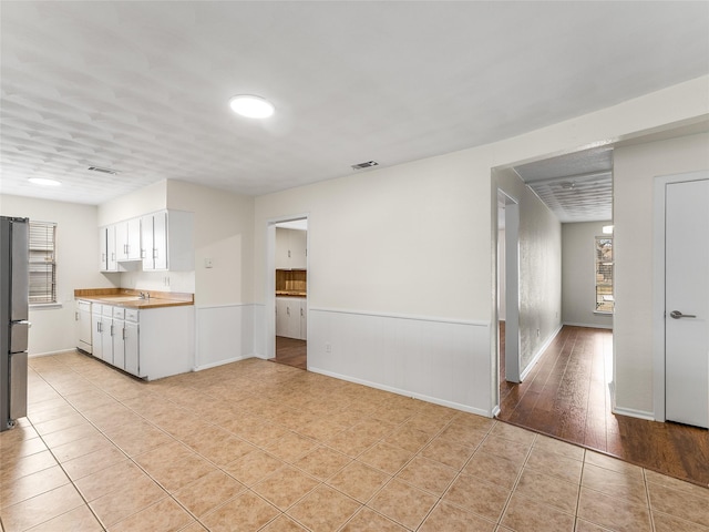 kitchen with white cabinetry, stainless steel fridge, and light tile patterned flooring