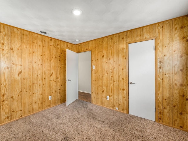 unfurnished room with wood walls and carpet flooring